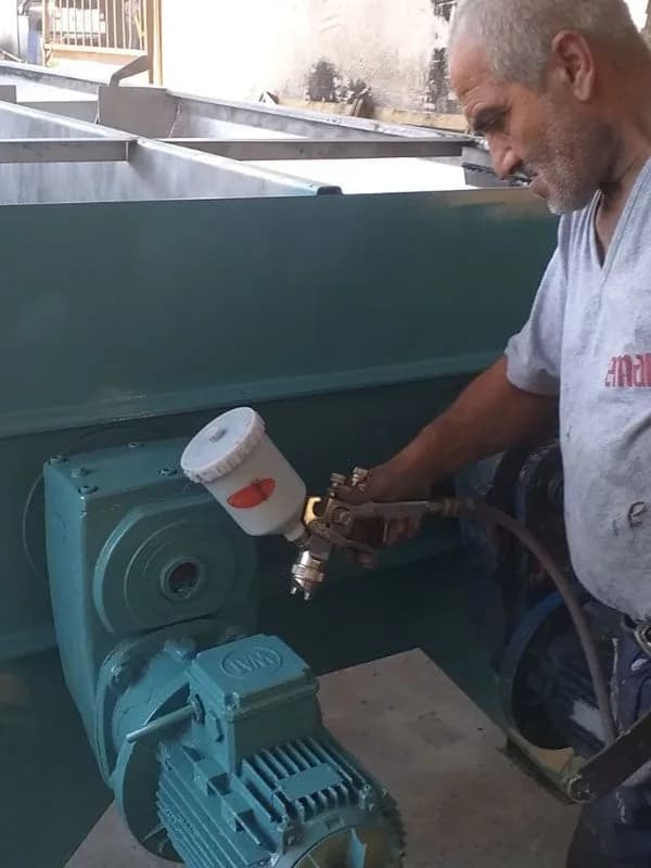 Mustafa Usta elinde boya tabancasıyla makine boyama işini yaparken